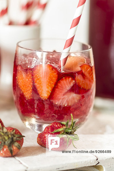 Glas eisgekühlter roter Früchtetee mit geschnittenen Erdbeeren und zerstoßenem Eis