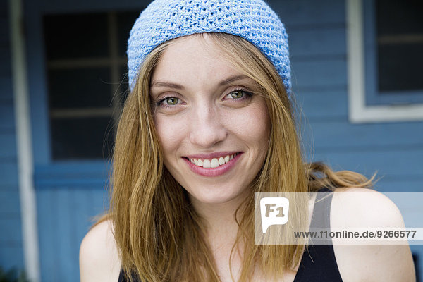 Porträt einer lächelnden jungen Frau mit hellblauer Haube