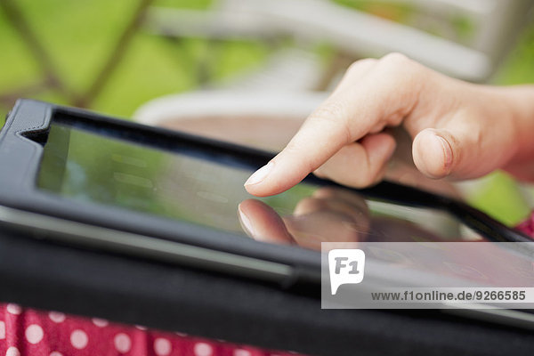 Finger einer jungen Frau beim Berühren des Displays eines digitalen Tabletts  Nahaufnahme