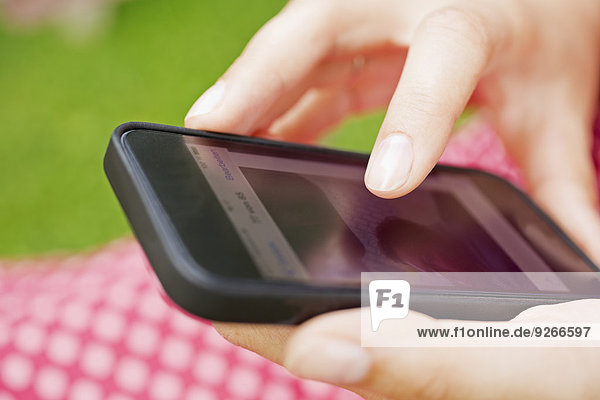 Finger einer jungen Frau berührt Display des Smartphones  Nahaufnahme