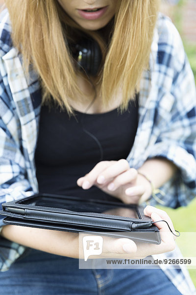 Junge Frau mit Kopfhörer um den Hals mit digitalem Tablett  Teilansicht