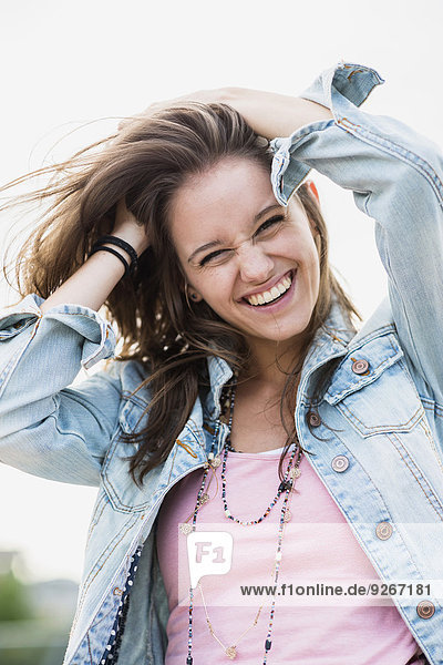 Portrait of laughing teenage girl with hands in her hair
