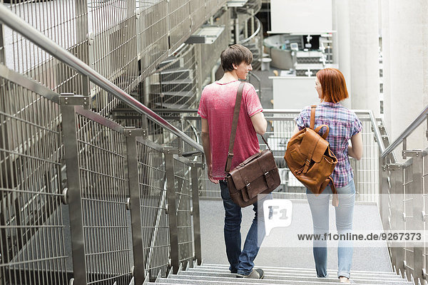 Zwei Studenten in einer Universitätsbibliothek gehen die Treppe hinunter.