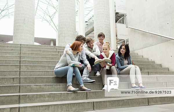 Studentengruppe mit Büchern auf der Treppe sitzend