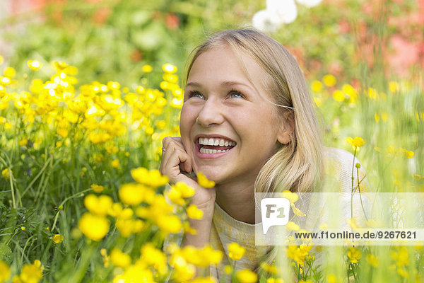 Portrait of happy teenage girl lying on a flower meadow