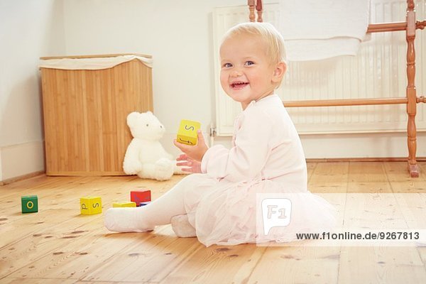 Portrait of smiling baby girl playing on floor with building blocks