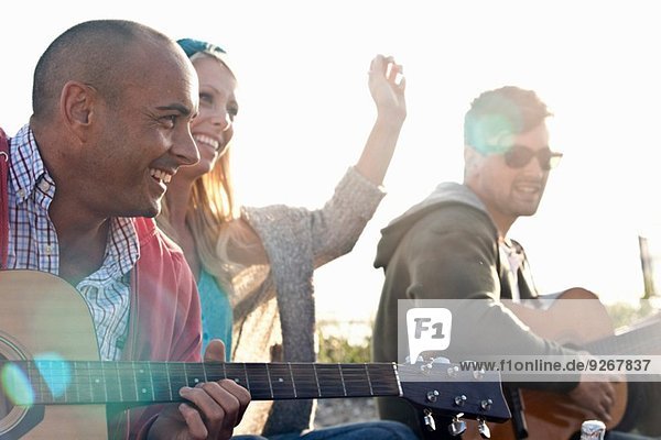 Drei erwachsene Freunde spielen Akustikgitarren am Bournemouth Beach  Dorset  UK