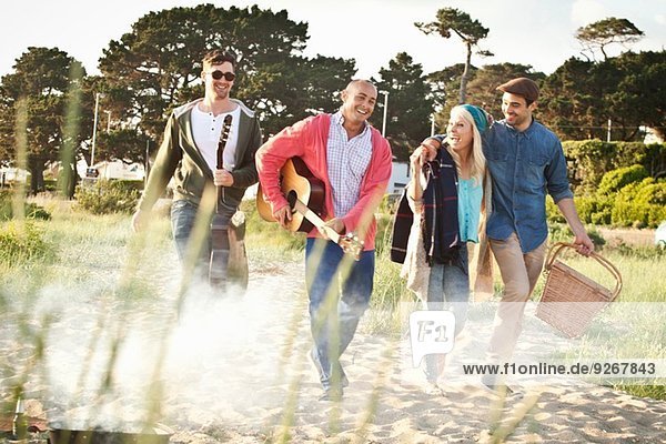 Vier erwachsene Freunde mit Akustikgitarre und Picknickkorb am Bournemouth Beach  Dorset  UK
