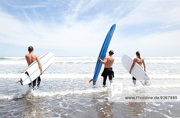 Männliche und weibliche Surferfreunde mit Surfbrettern im Meer stehend