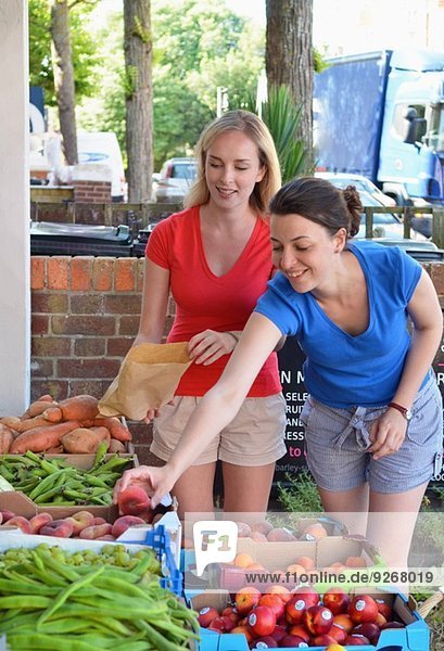 Zwei junge Frauen wählen Obst am Marktstand