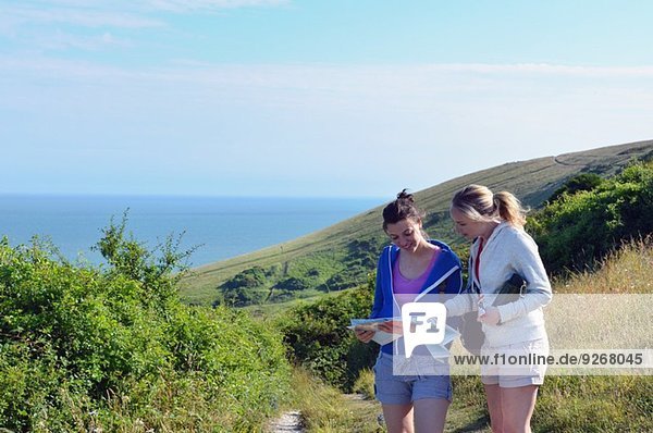 Two young women on coastal path with map
