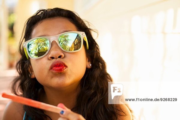 Portrait of girl with red lips and ice lolly stick pulling face