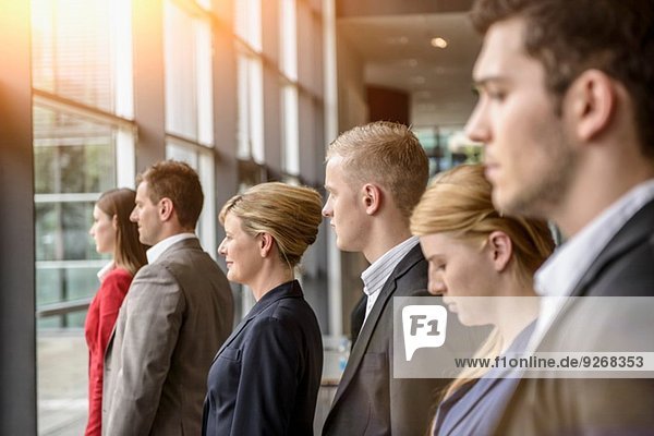 Group of serious businesswomen and men standing in a row