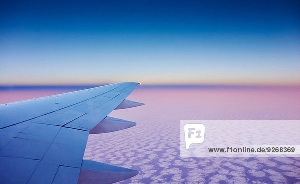 Atmosphärische Höhenansicht des Flugzeugflügels über den Wolken
