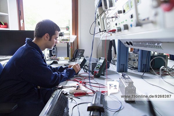 Male electrician repairing electronic equipment in workshop