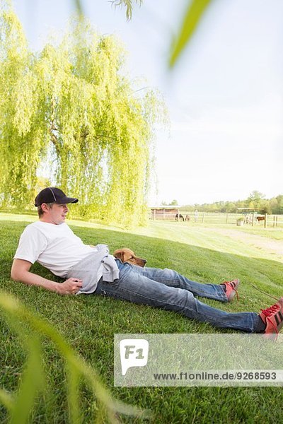 Mann entspannt auf Rasen mit Hund