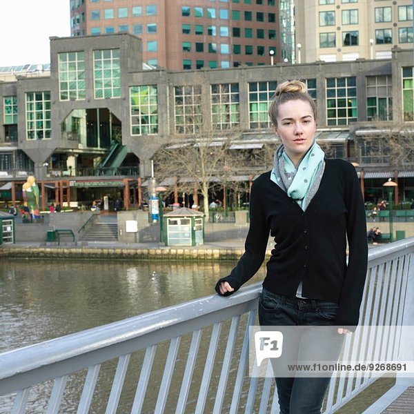Porträt der selbstbewussten jungen Frau auf der Flussbrücke in der Stadt
