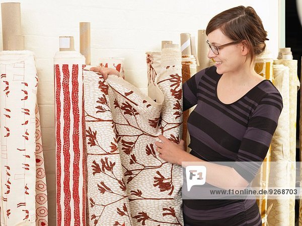 Frau zeigt Stoff in handbedruckter Textilwerkstatt