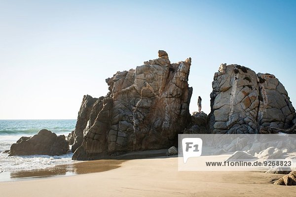 Junge Frau auf Felsen am Strand stehend