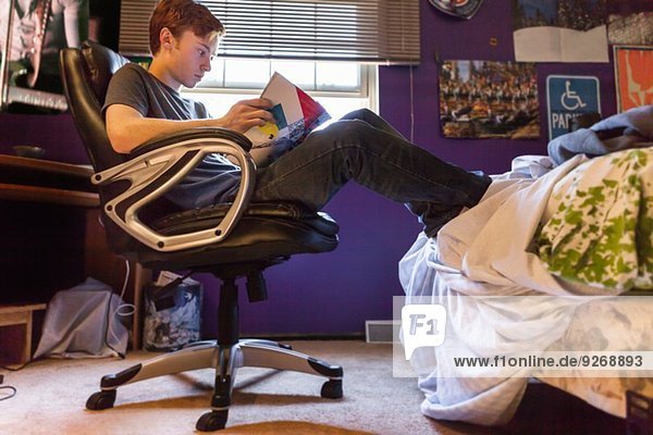 Teenager reading magazine at home