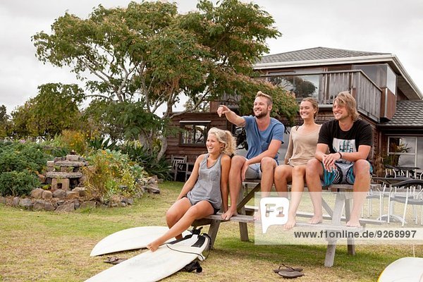Vier Surferfreunde sitzen auf der Picknickbank