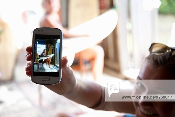 Junge Frau hält Smartphone mit Foto ihrer besten Freundin hoch