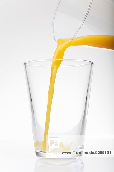 Frischer Orangensaft aus dem Krug in das Trinkglas