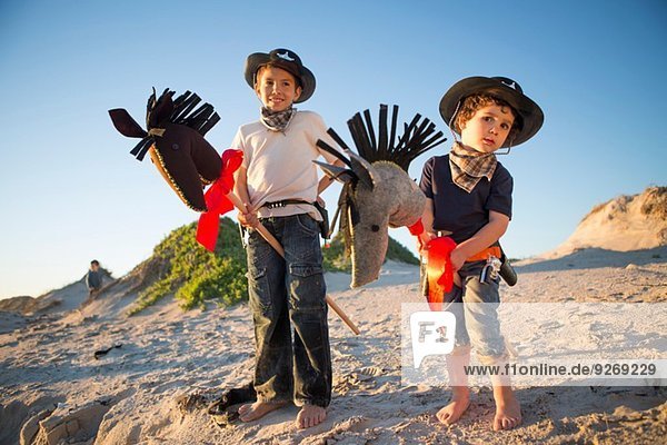 Two brothers dressed as cowboy's with hobby horse's