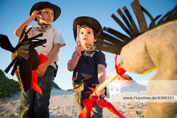 Zwei Brüder verkleidet als Cowboys mit Spielzeugpistole und Hobbypferd.