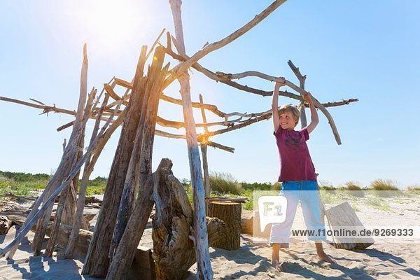 Junge hebt Treibholz zum Bau einer Unterkunft,  Caleri Beach,  Veneto,  Italien