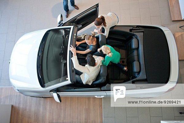 Overhead-Ansicht der Familie beim Ausprobieren des Cabrios im Autohaus