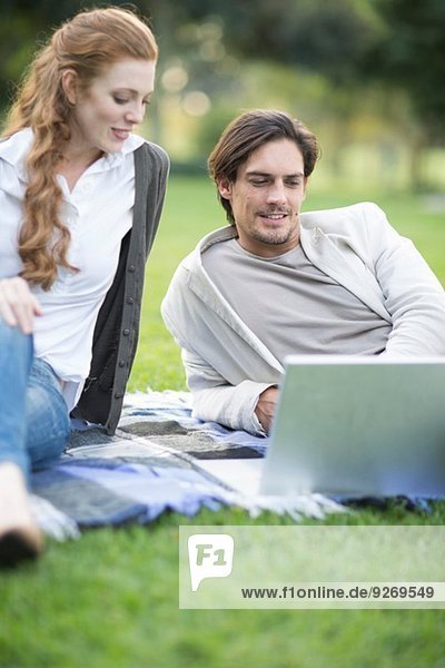 Geschäftsmann und Kollegin beim Blick auf den Laptop im Park