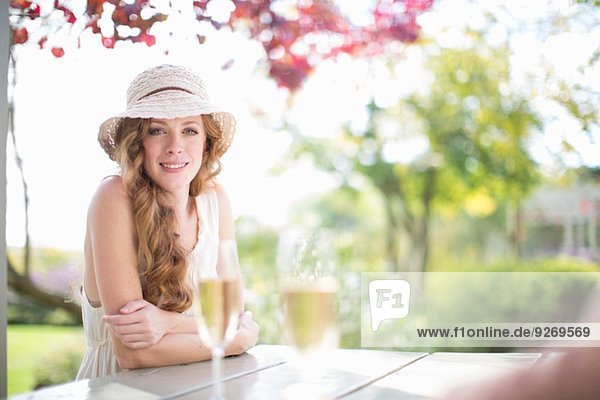 Portrait der schönen jungen Frau bei Tisch im Gartenrestaurant