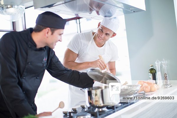 Two male chefs cooking on hob in commercial kitchen