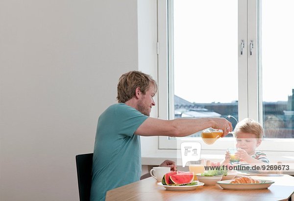 Vater und Kleinkind beim Frühstück am Küchentisch