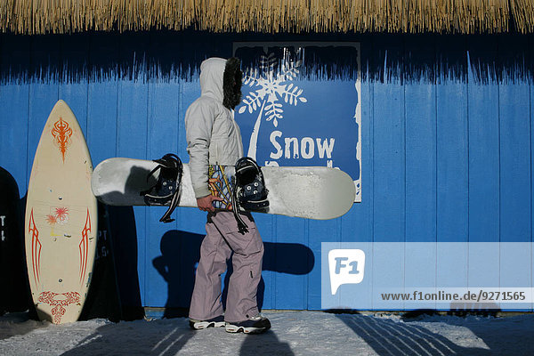 stehend Frau Snowboard halten Seitenansicht