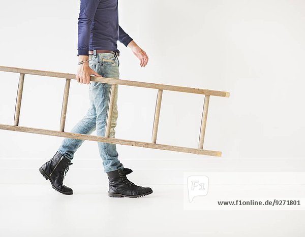 Low section of man carrying ladder