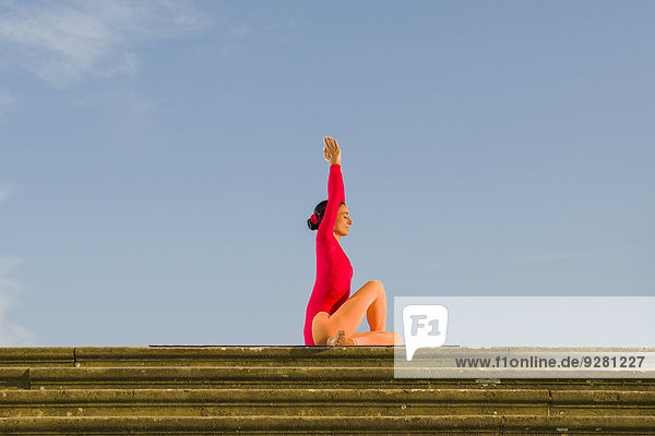Junge Frau praktiziert Hatha-Yoga im Freien  in Ardha Matsyendrasana-Haltung  halbe Rückendrehung