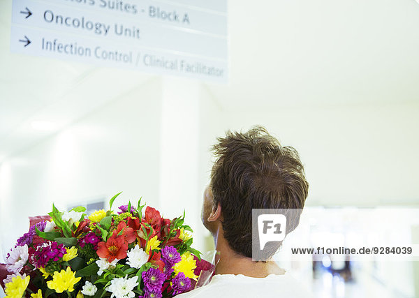 Mann mit Blumenstrauß im Krankenhaus