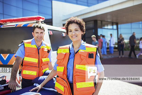 Paramedics smiling by ambulance in hospital parking lot