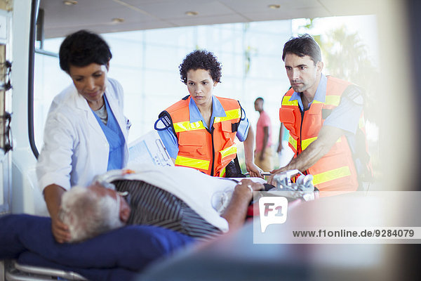 Rettungssanitäter und Krankenschwester,  die den Patienten im Krankenwagen untersuchen.