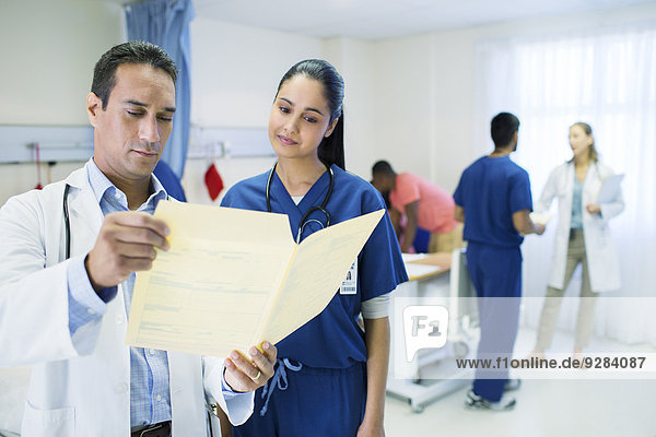 Doctor and nurse reading medical chart in hospital room