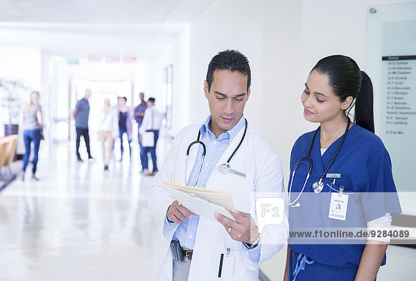 Arzt und Krankenschwester beim Lesen der Krankenakte im Flur des Krankenhauses