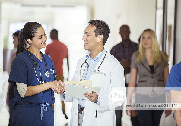 Doctor and nurse shaking hands in hospital hallway
