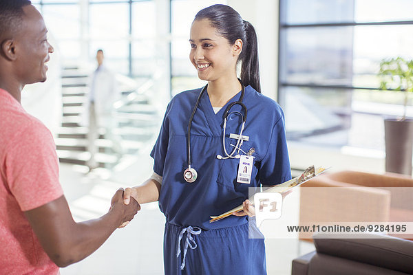 Krankenschwester und Patientin beim Händeschütteln im Krankenhaus