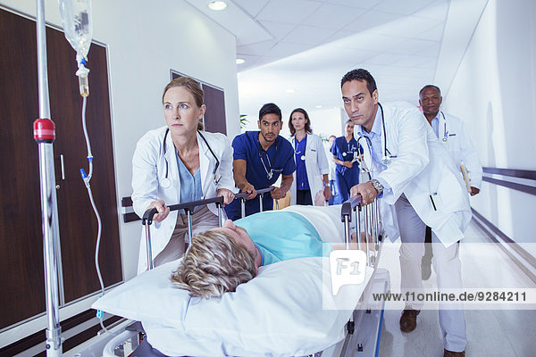 Doctors and nurses wheeling patient down hospital hallway