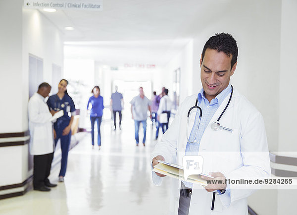 Arzt beim Lesen der Krankenakte im Krankenhausflur