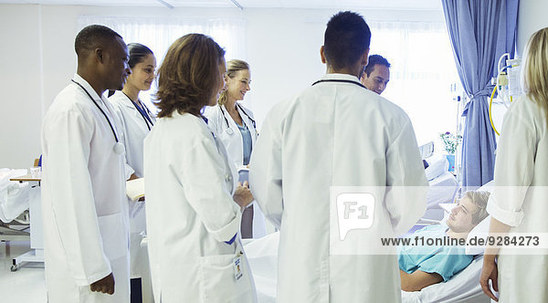 Arzt und Assistenzärzte untersuchen Patienten im Krankenhauszimmer