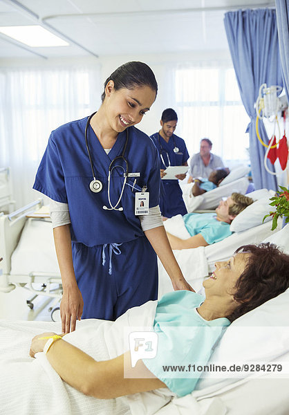 Krankenschwester im Gespräch mit Patientin im Krankenhauszimmer