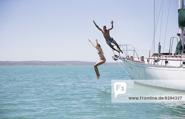 Couple jumping off boat into water